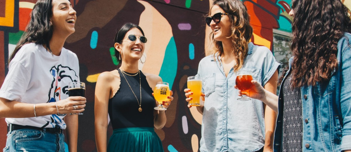 Four friends, each with a beverage in their hand