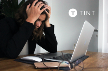 woman holding her head while working at laptop